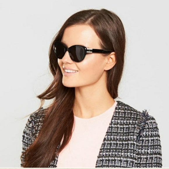 Woman wearing black sunglasses with a light gray background